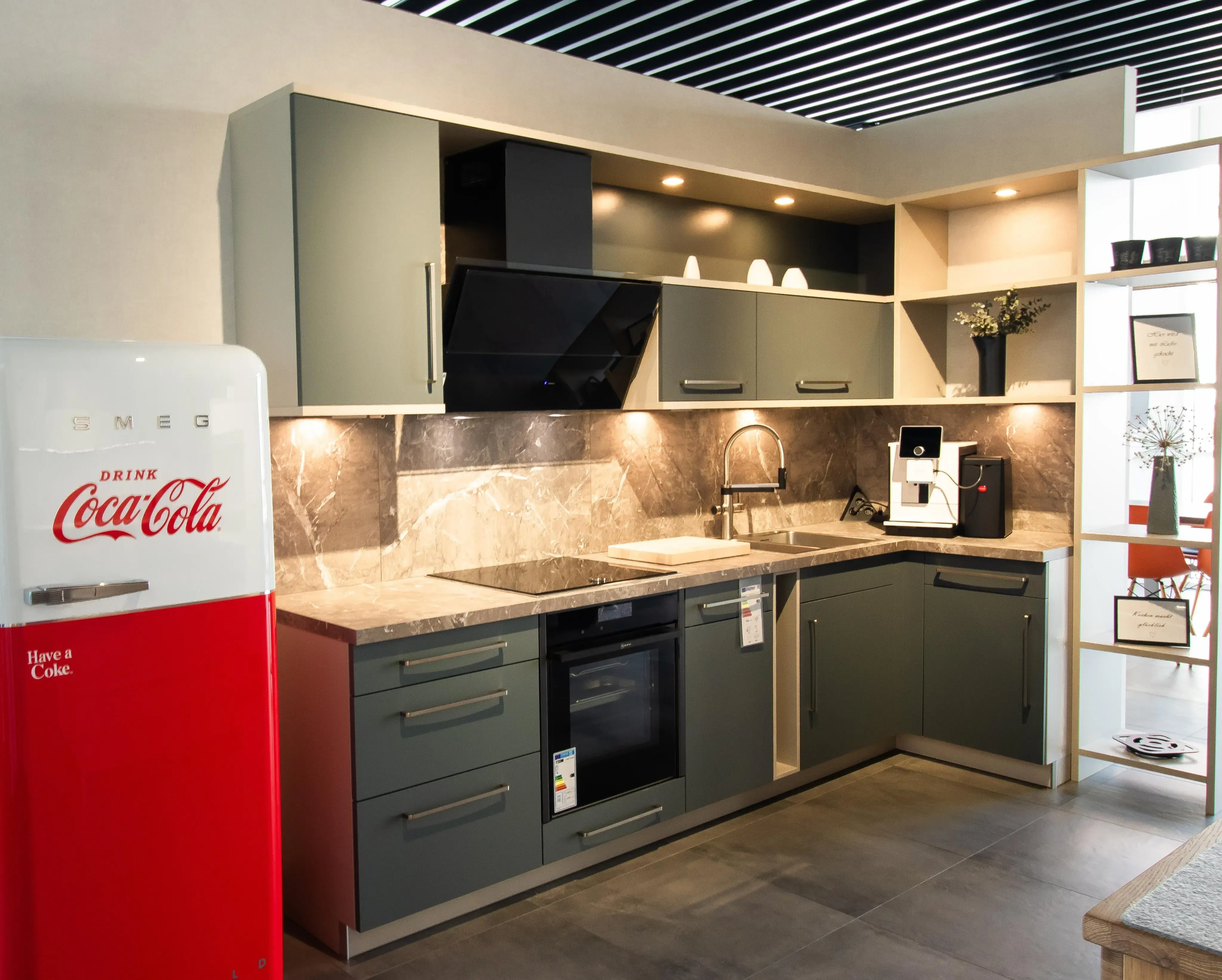 Moderne Küche mit grauen Schränken, rotem Coca-Cola-Kühlschrank und Kaffeemaschine.
