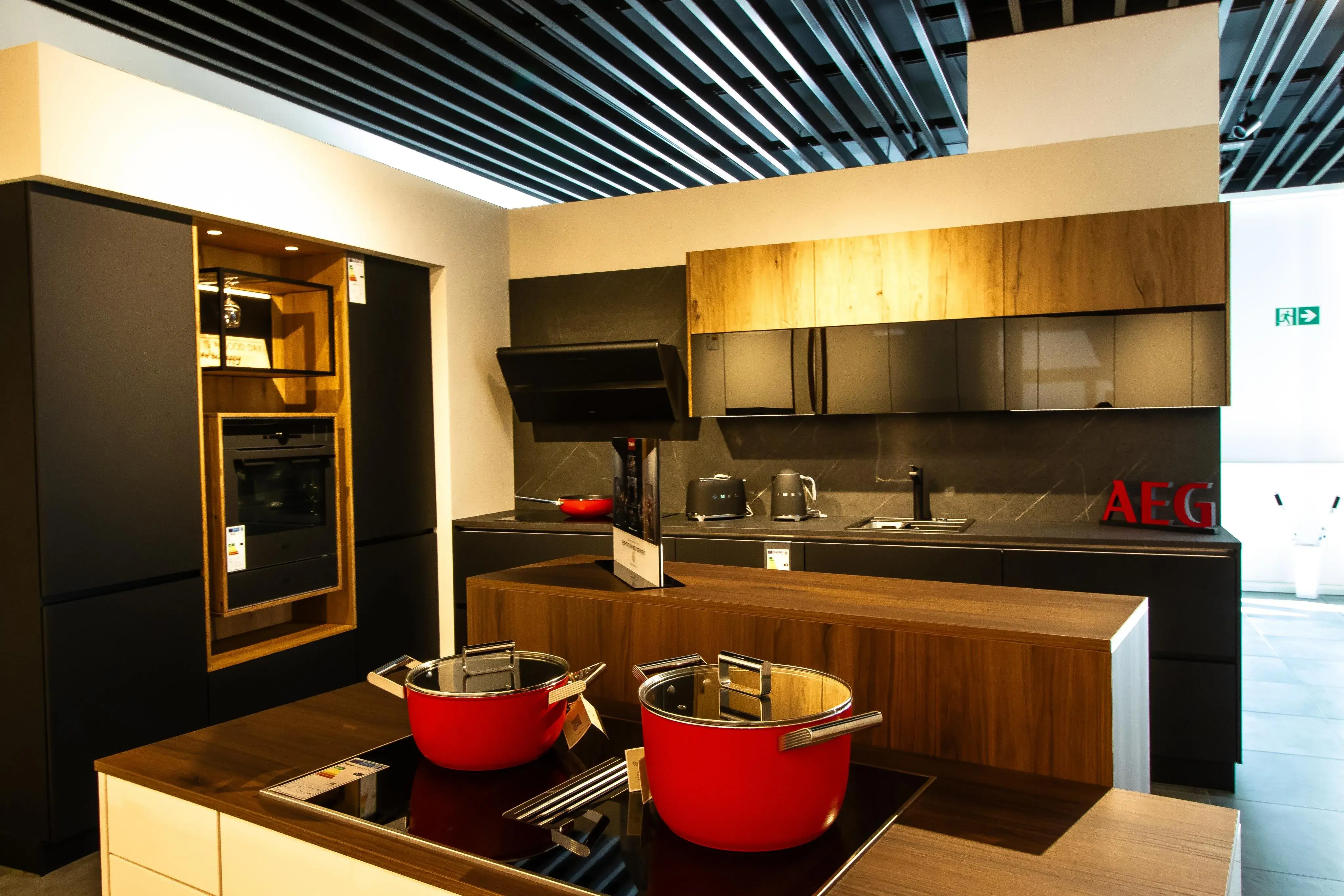 Moderne Küche mit Holzfronten, Kochinsel, roten Töpfen und Einbaugeräten