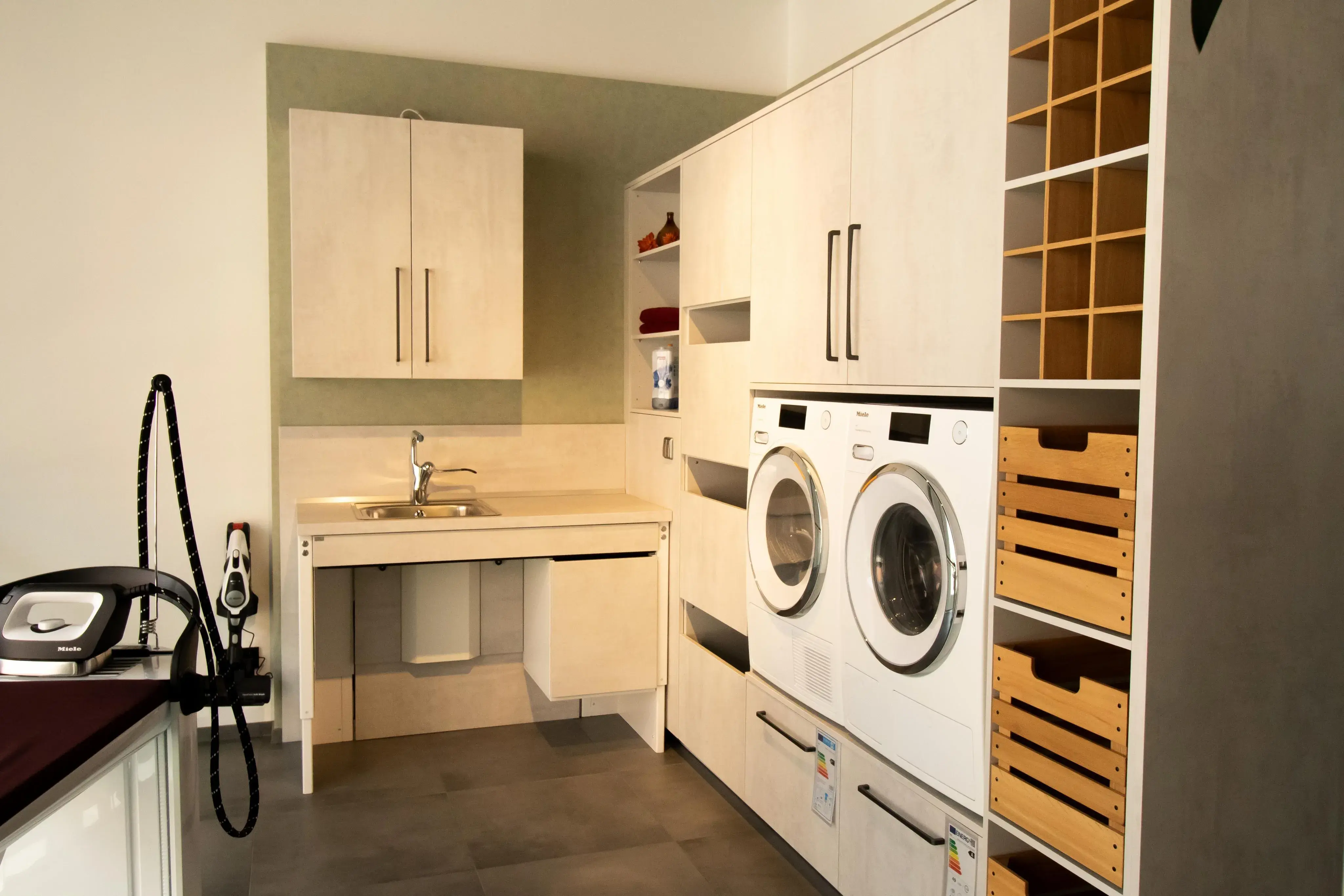 Moderne Waschküche mit Waschmaschine, Trockner, Spüle und hellen Holzschränken